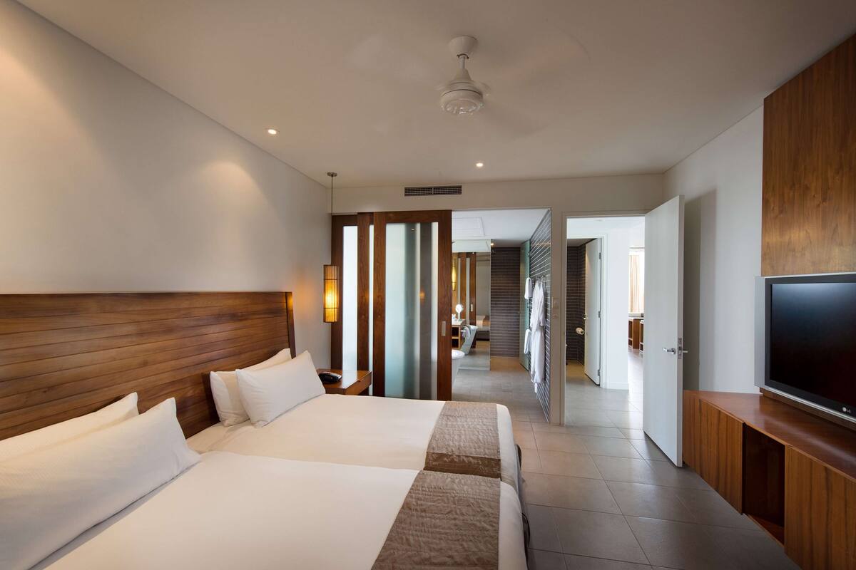 Ein modernes Hotelzimmer mit zwei Betten, einem Fernseher und Blick auf den Flur.