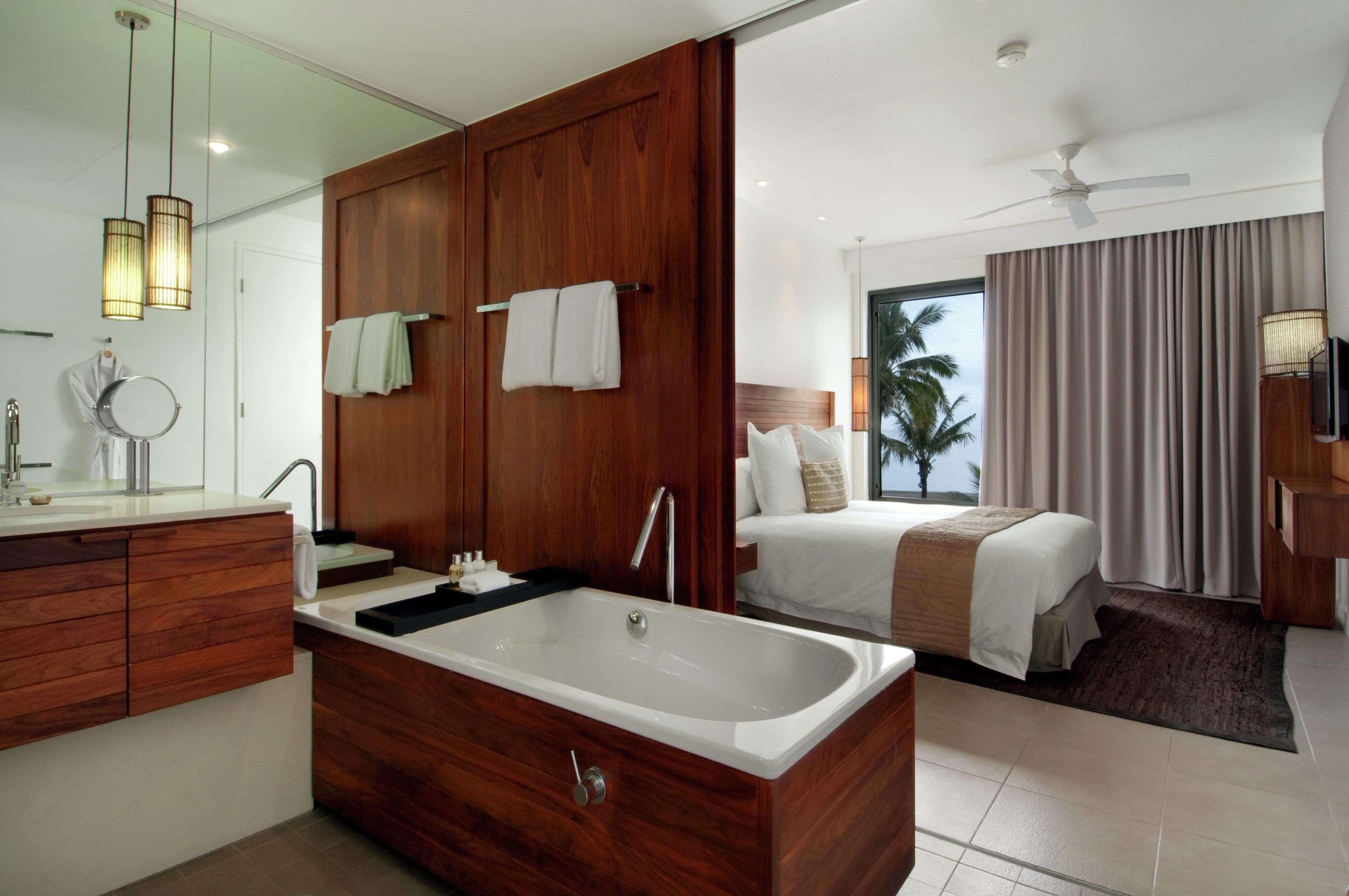 A modern bathroom with a large bathtub, wooden vanity, and a mirror.