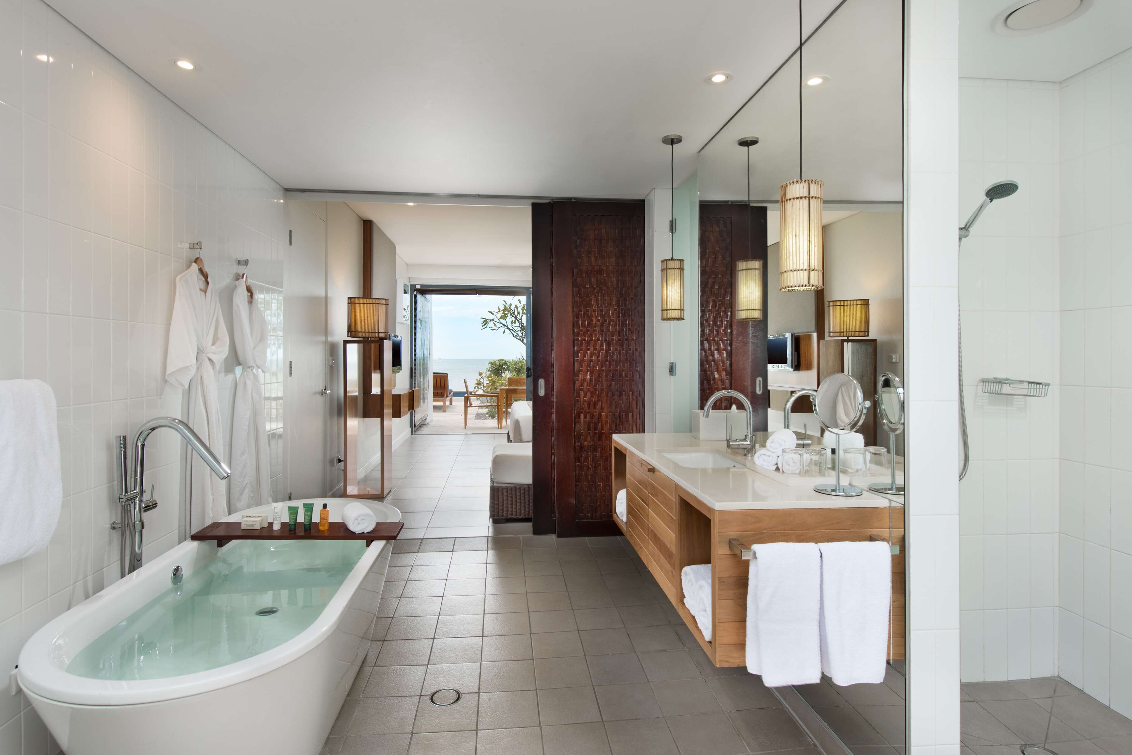 Un baño moderno con una bañera independiente, un tocador con espejo y zona de ducha.