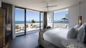 A modern hotel room with a large bed, a TV, and a balcony with a view of the sea. - Hilton Fiji Beach Resort and Spa (Nadi)