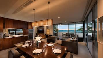 A modern kitchen with a dining area, large windows, and a view of the ocean.