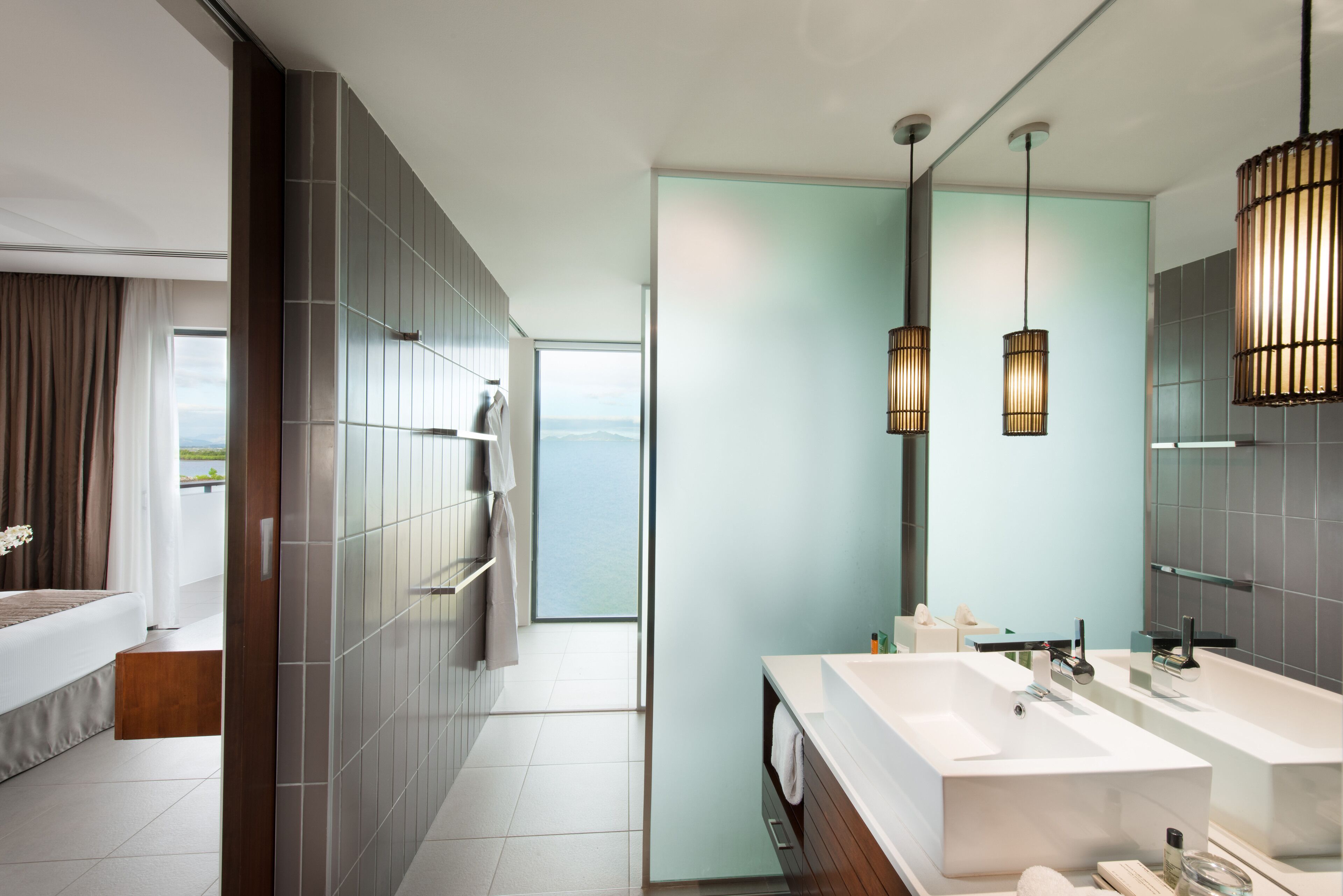 A modern bathroom with a large mirror, two sinks, and a shower area.