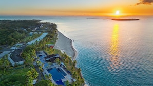 An aerial view of a resort with a beachfront, a pool area, and a sunset over the ocean. - Hilton Fiji Beach Resort and Spa (Nadi)