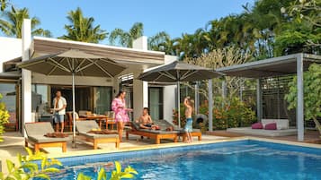 Zona junto a la piscina con sillas de descanso, sombrillas y una piscina.