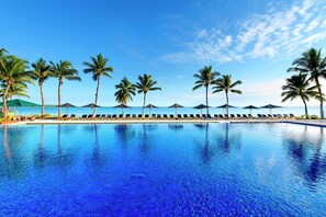 A poolside area with lounge chairs and umbrellas, palm trees, and a clear sky. - Hilton Fiji Beach Resort and Spa (Nadi)