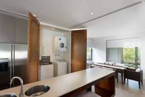 Una cocina moderna con electrodomésticos de acero inoxidable, una isla grande con un lavamanos y una zona de comedor con mesa y sillas.