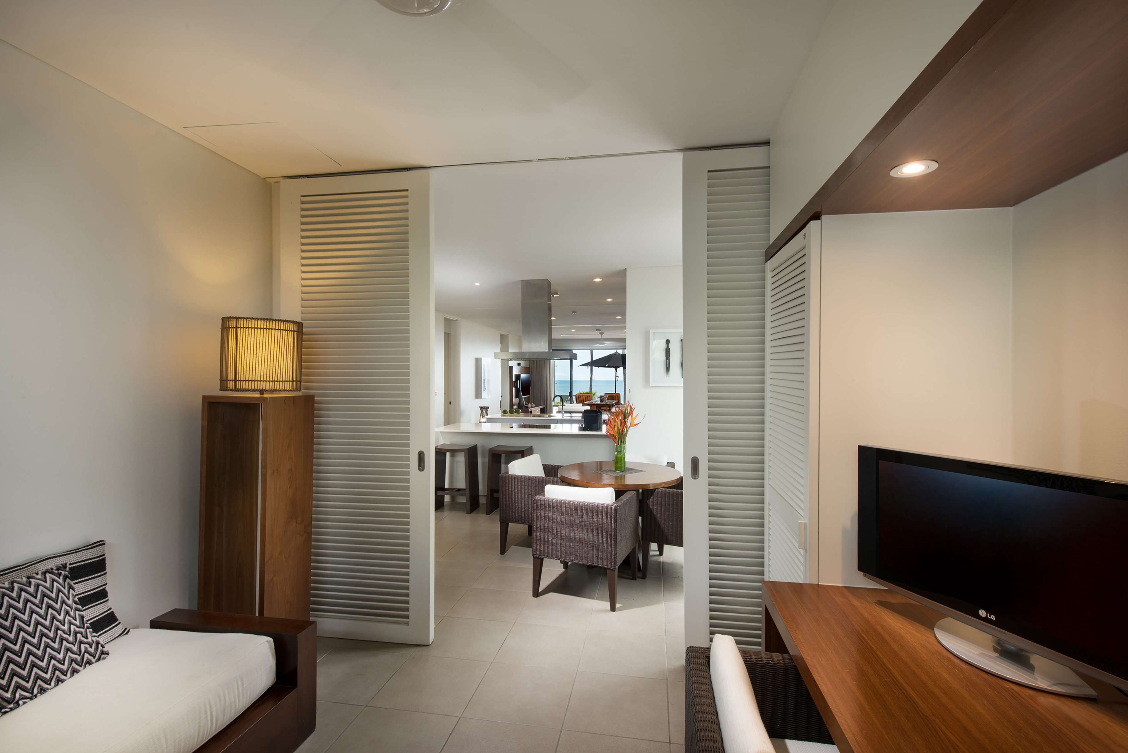 Una habitación de hotel moderna con una cama, un televisor, una mesita de madera y un área de comedor con mesa y sillas.