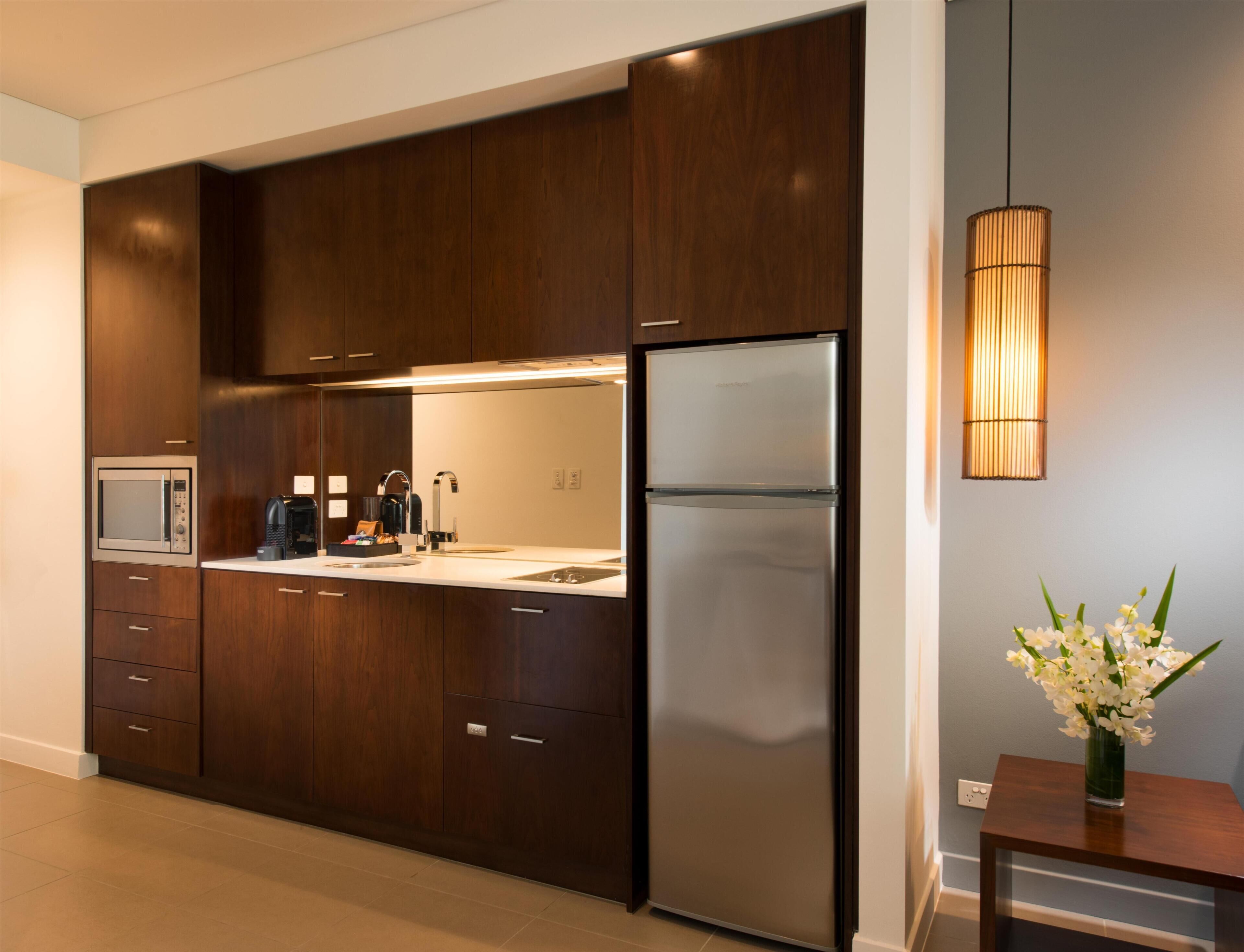 A modern kitchen with dark wood cabinets, stainless steel appliances, and a built-in microwave.