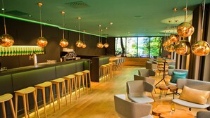 A modern bar area with wooden stools, a bar counter, and hanging spherical light fixtures. - Arcadeon (Hagen)
