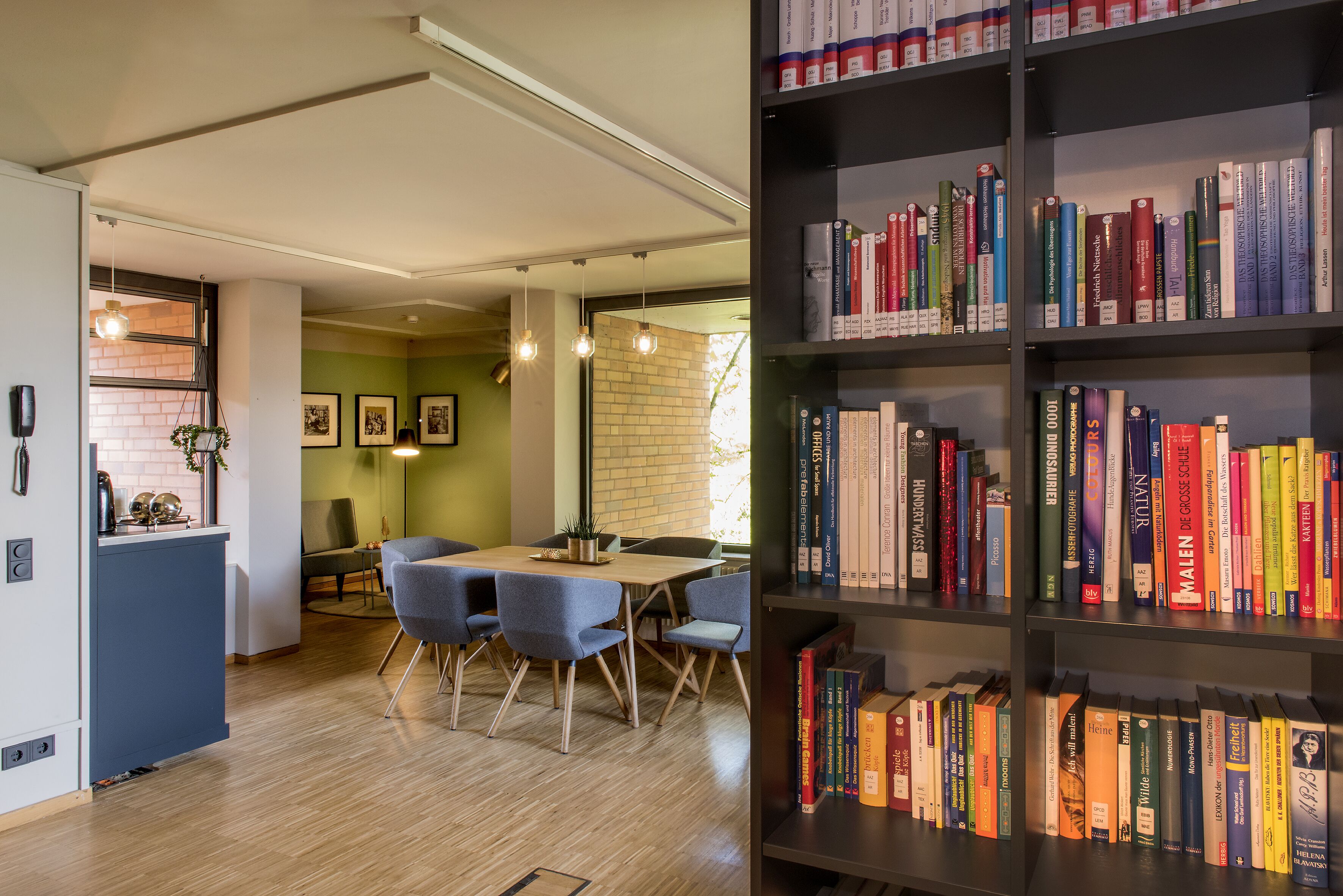 Eine moderne Küche mit Essbereich, Holzboden und einer Bücherwand.