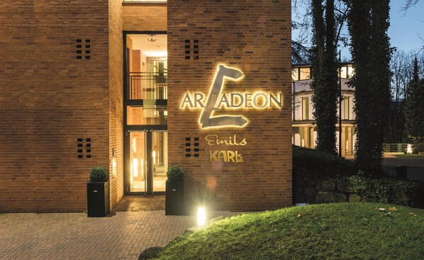 A building with a prominent illuminated sign reading 'ARADEN Emil Karl' and a glass entrance. - Arcadeon (Hagen)