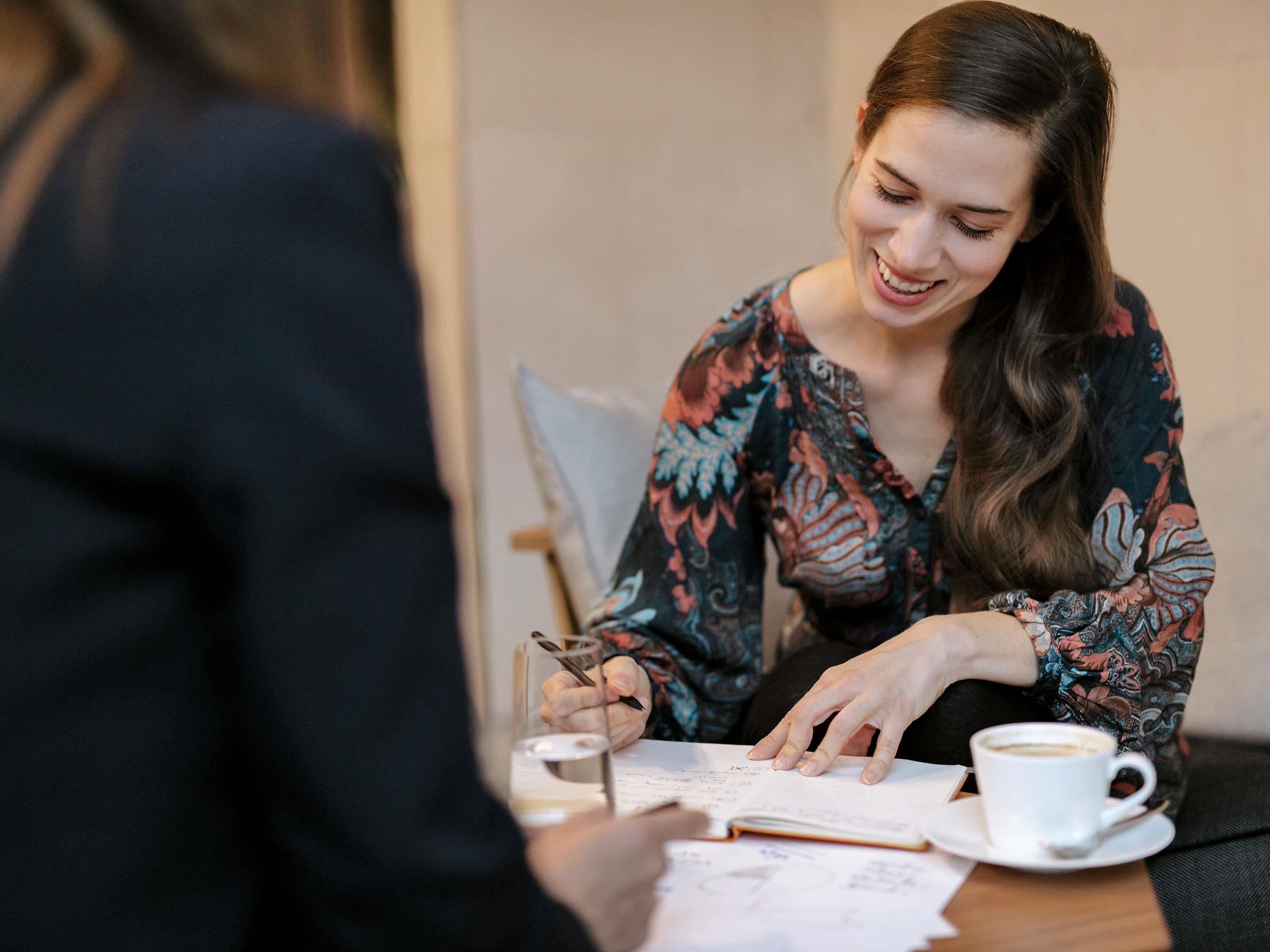 A person sitting at a table with a cup of coffee, papers, and a pen.