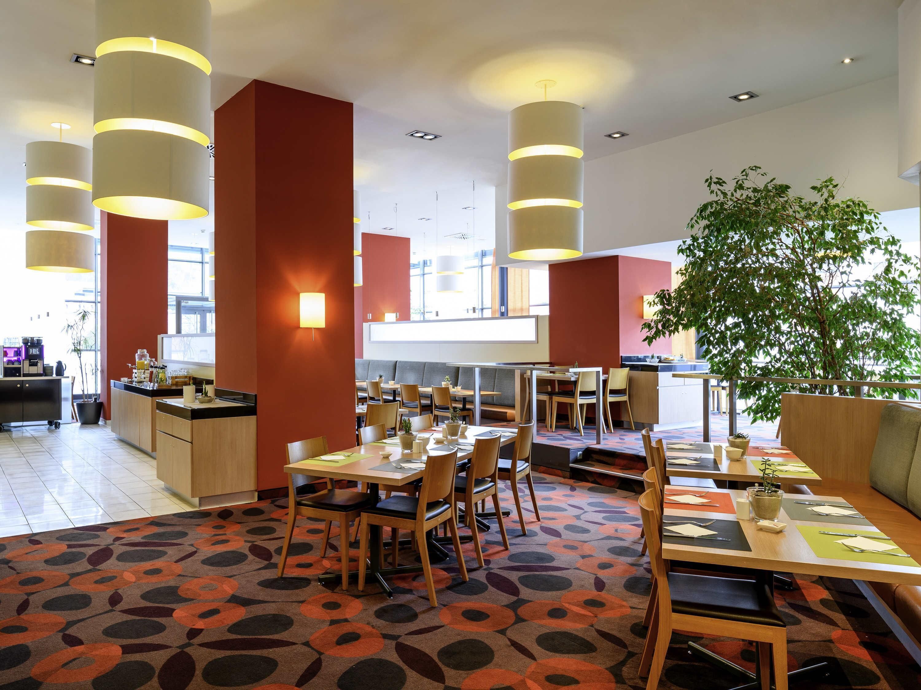 Un restaurante moderno con techos altos, iluminación colgante y una alfombra estampada.