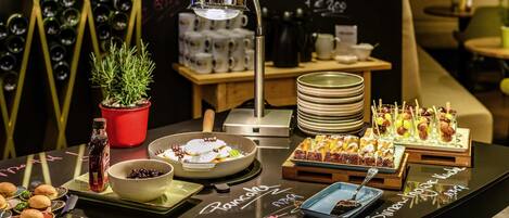 Una mesa de buffet con diversos alimentos, una planta en maceta y un menú en pizarra.