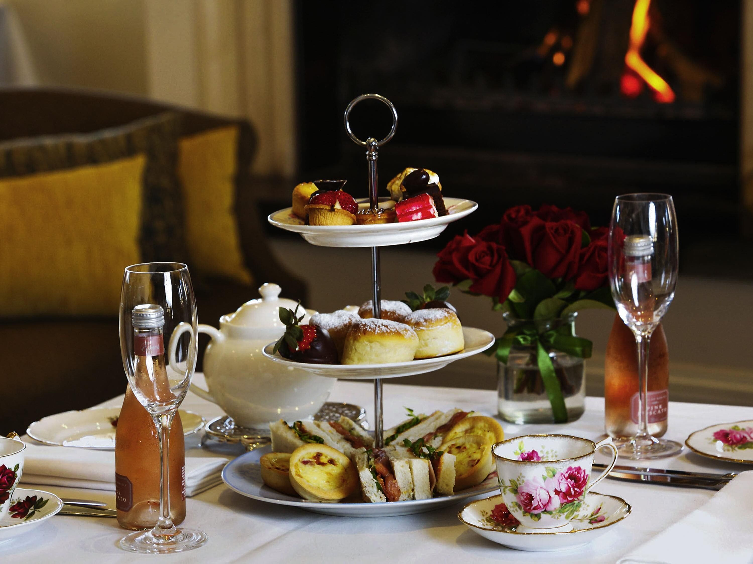 A three-tiered dessert stand with pastries and a teapot on a table.