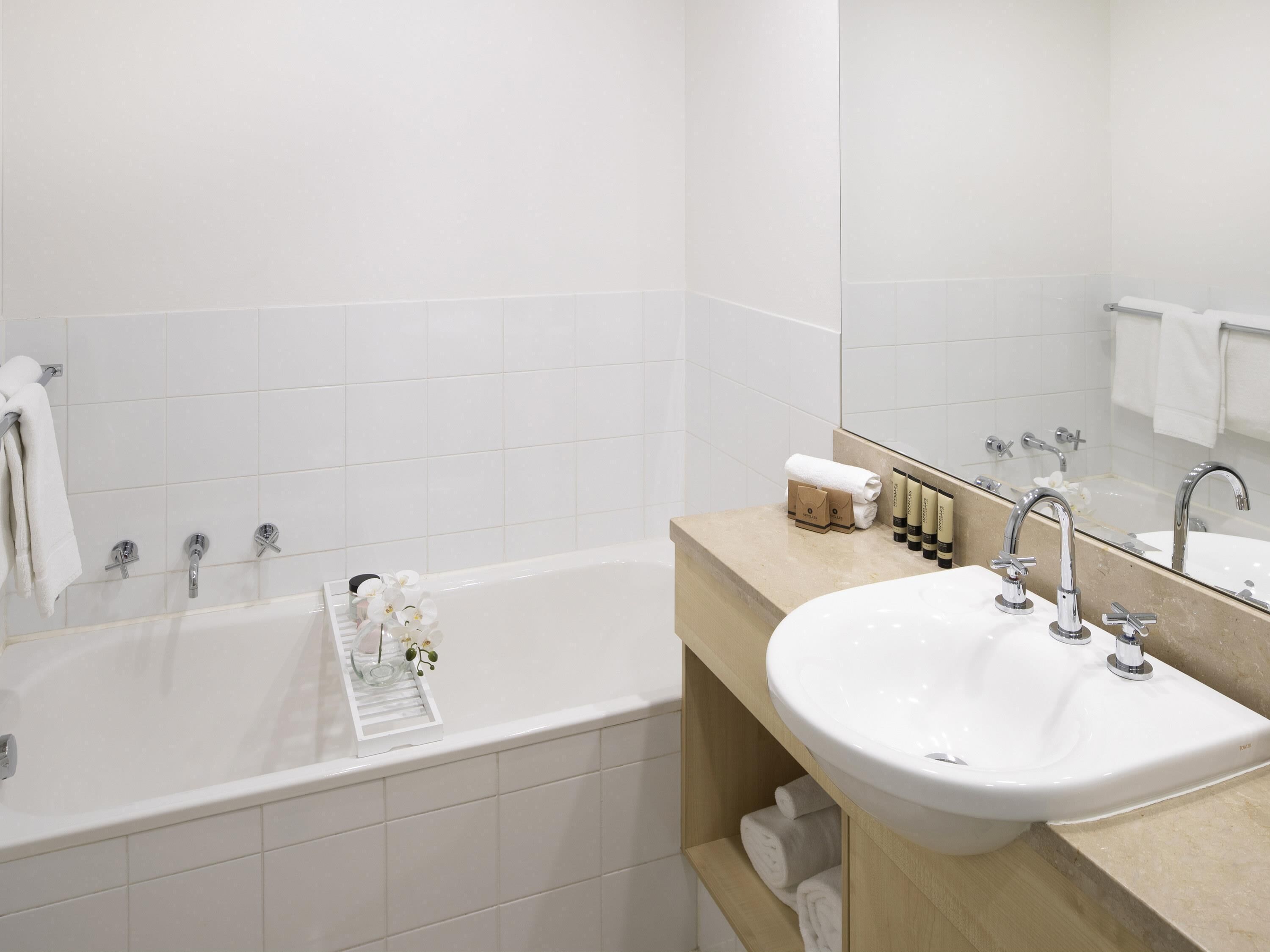 A modern bathroom with a bathtub, a sink, and a mirror.