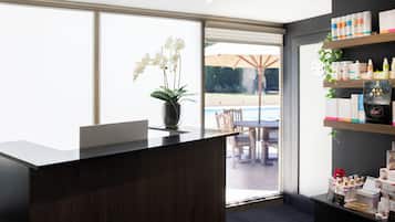 Welcome to our reception area, featuring a spacious desk and a beautiful orchid, with stunning views of the outdoor pool and patio.