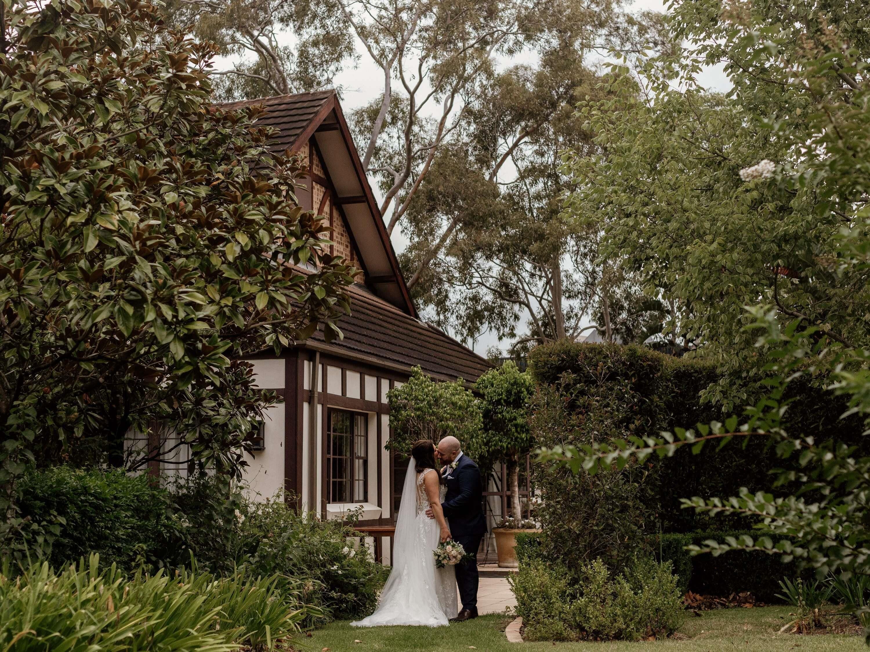 A couple in a garden with a building in the background.