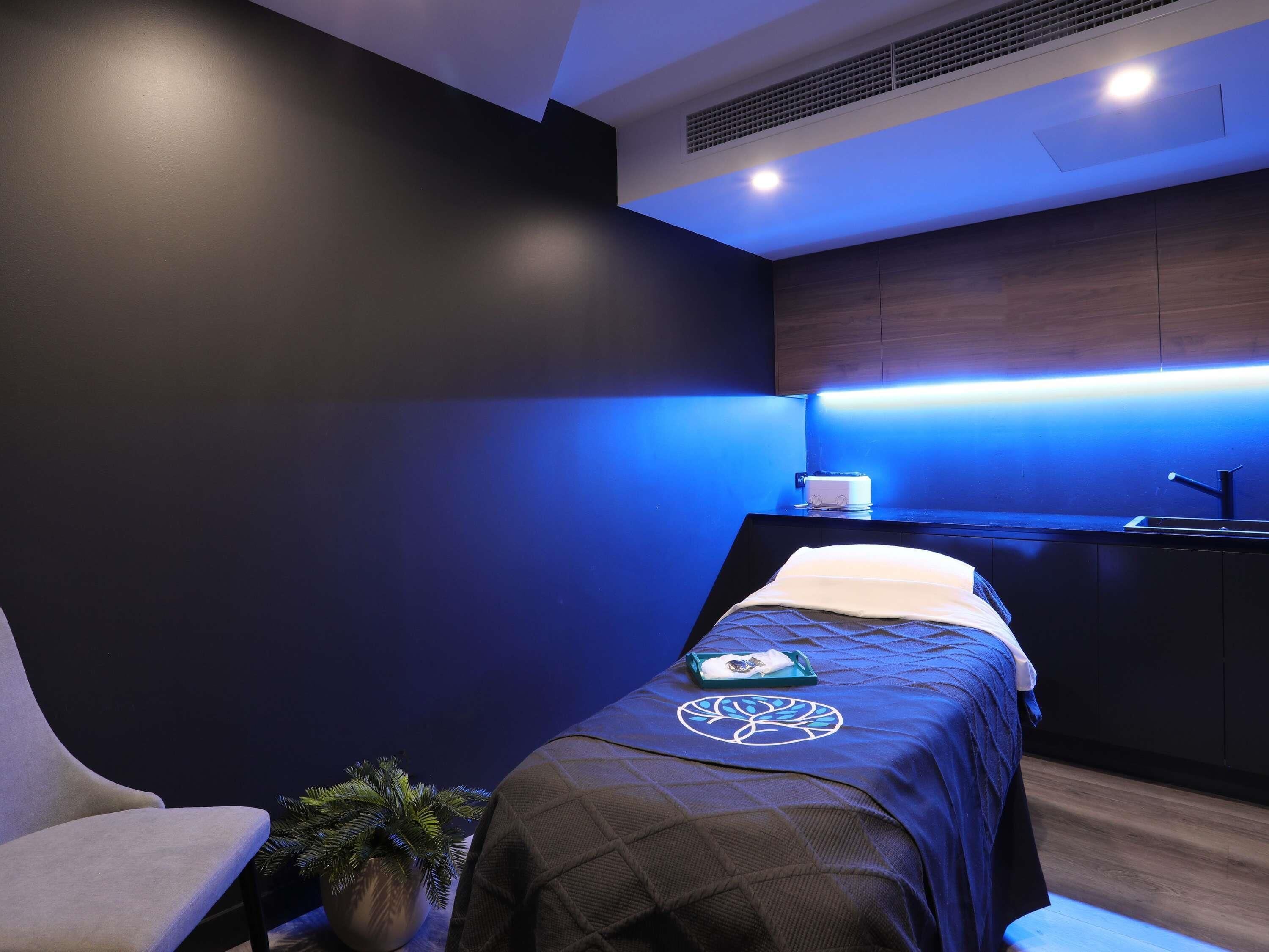 A modern room with a bed, a chair, a small table, and a potted plant.