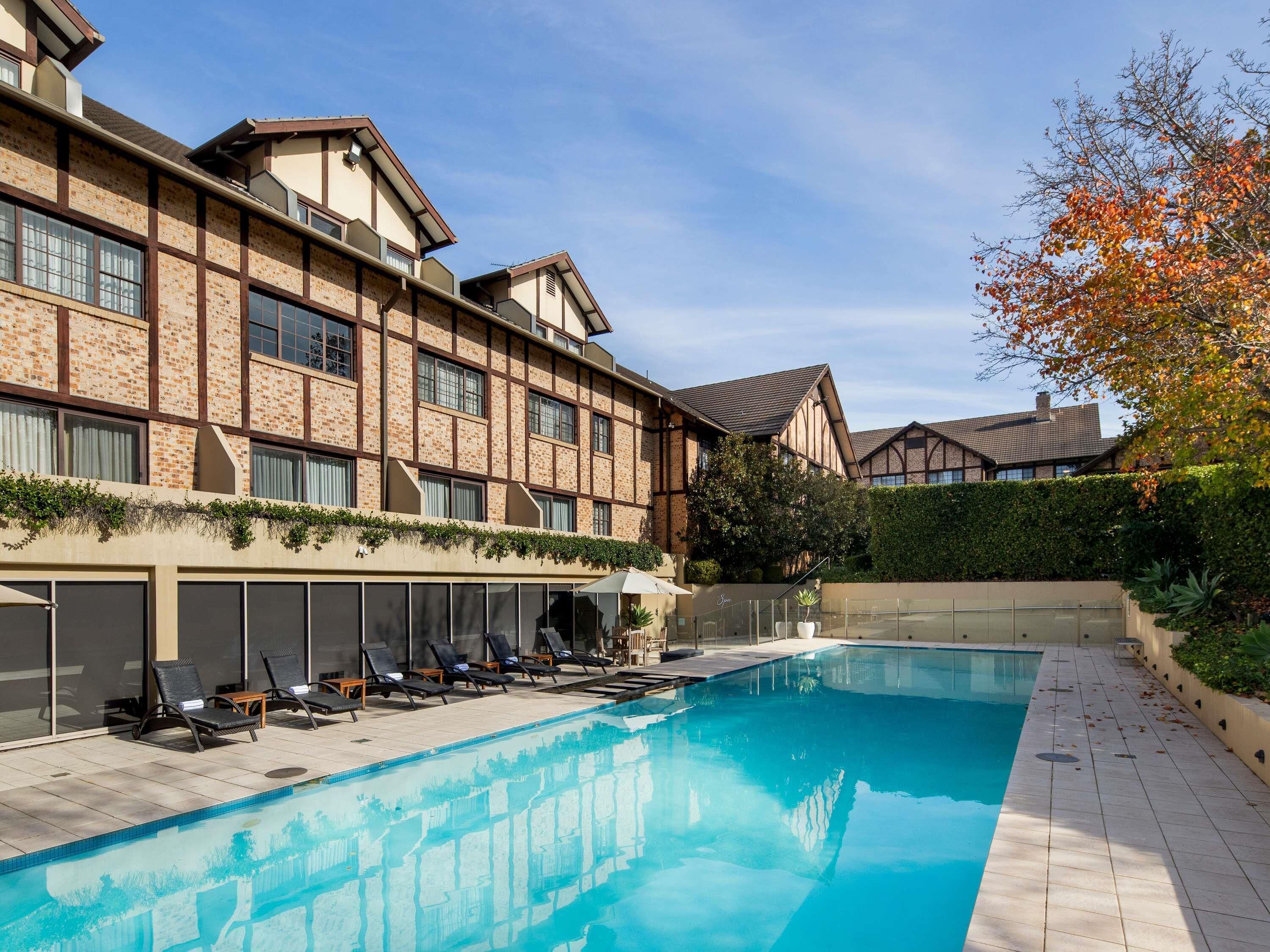 Un hotel con piscina, sillones de descanso y fachada de ladrillo.