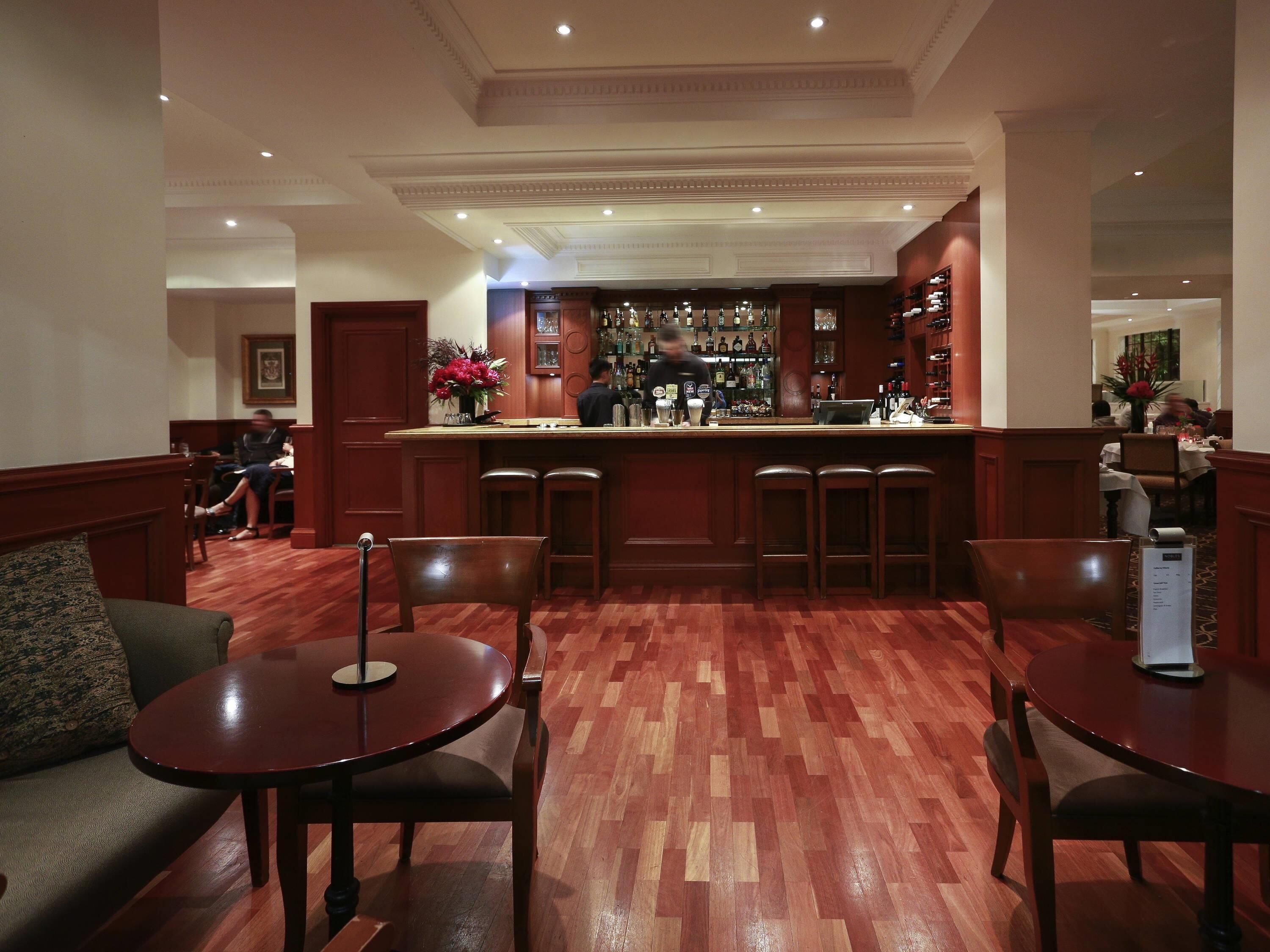 A bar area with a counter, stools, and a seating area with tables and chairs.