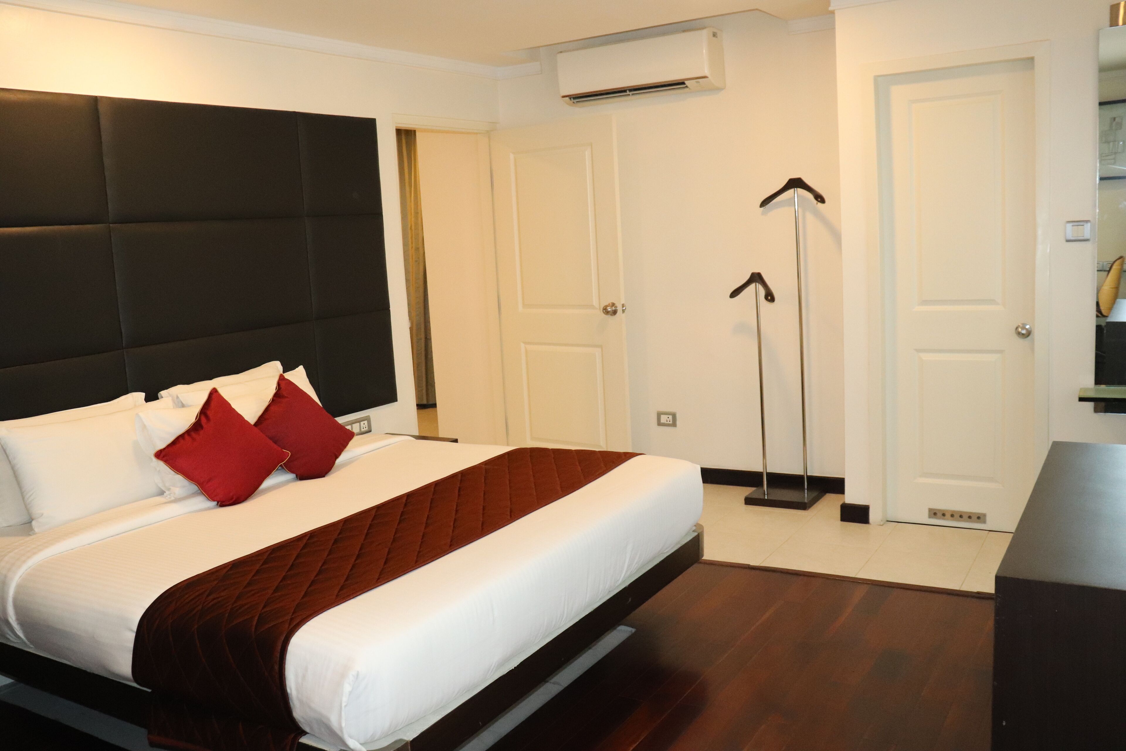 Ein modernes Hotelzimmer mit einem großen Bett, einem dunklen Kopfteil und einer weißen Tür.