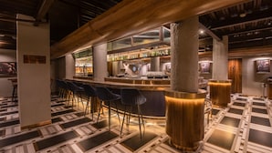 A bar area with a modern design, featuring a bar counter, stools, and a patterned floor. - 37th Crescent Hotel (Bengaluru)