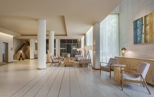 A spacious lobby with a central seating area, a staircase, and a reception desk.