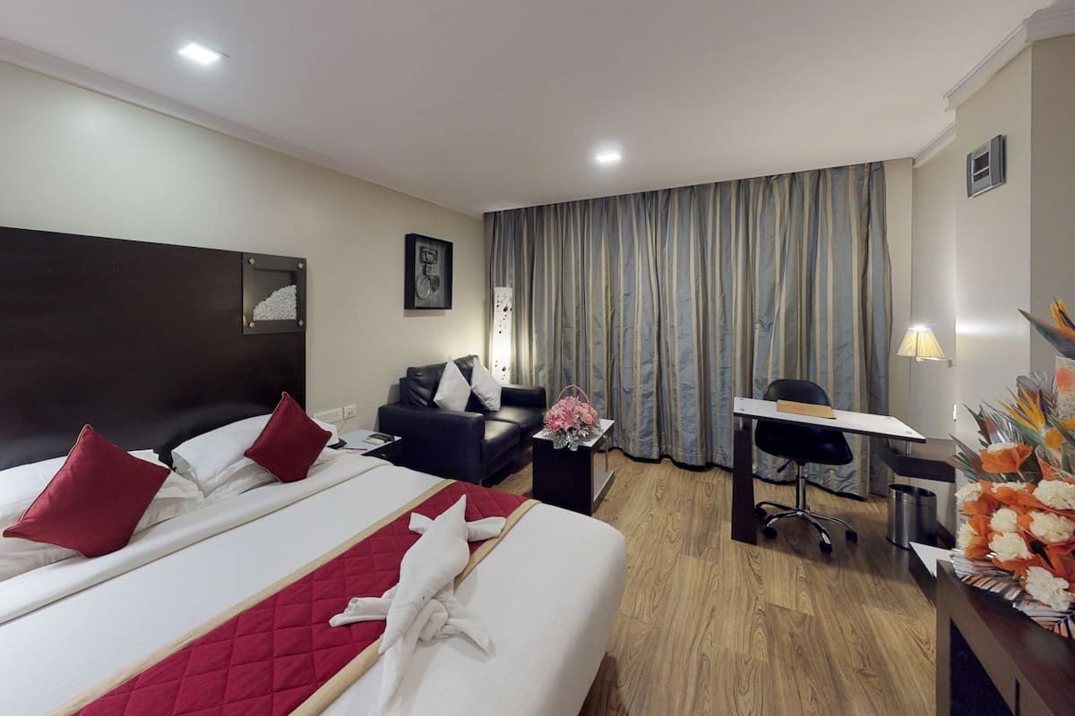 A hotel room with two beds, a desk, a chair, a small table, and a window with curtains.