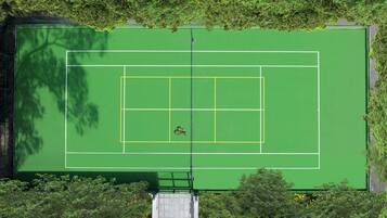 Vista aérea de una cancha de tenis rodeada de árboles.