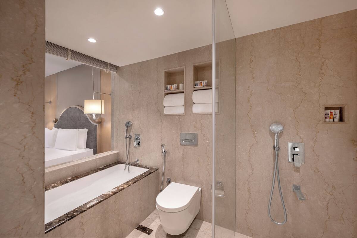 Ein modernes Badezimmer mit Marmorwaschbecken, Toilette, Dusche und einem großen Spiegel.