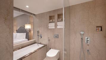 A modern bathroom with a marble sink, a toilet, a shower, and a large mirror.