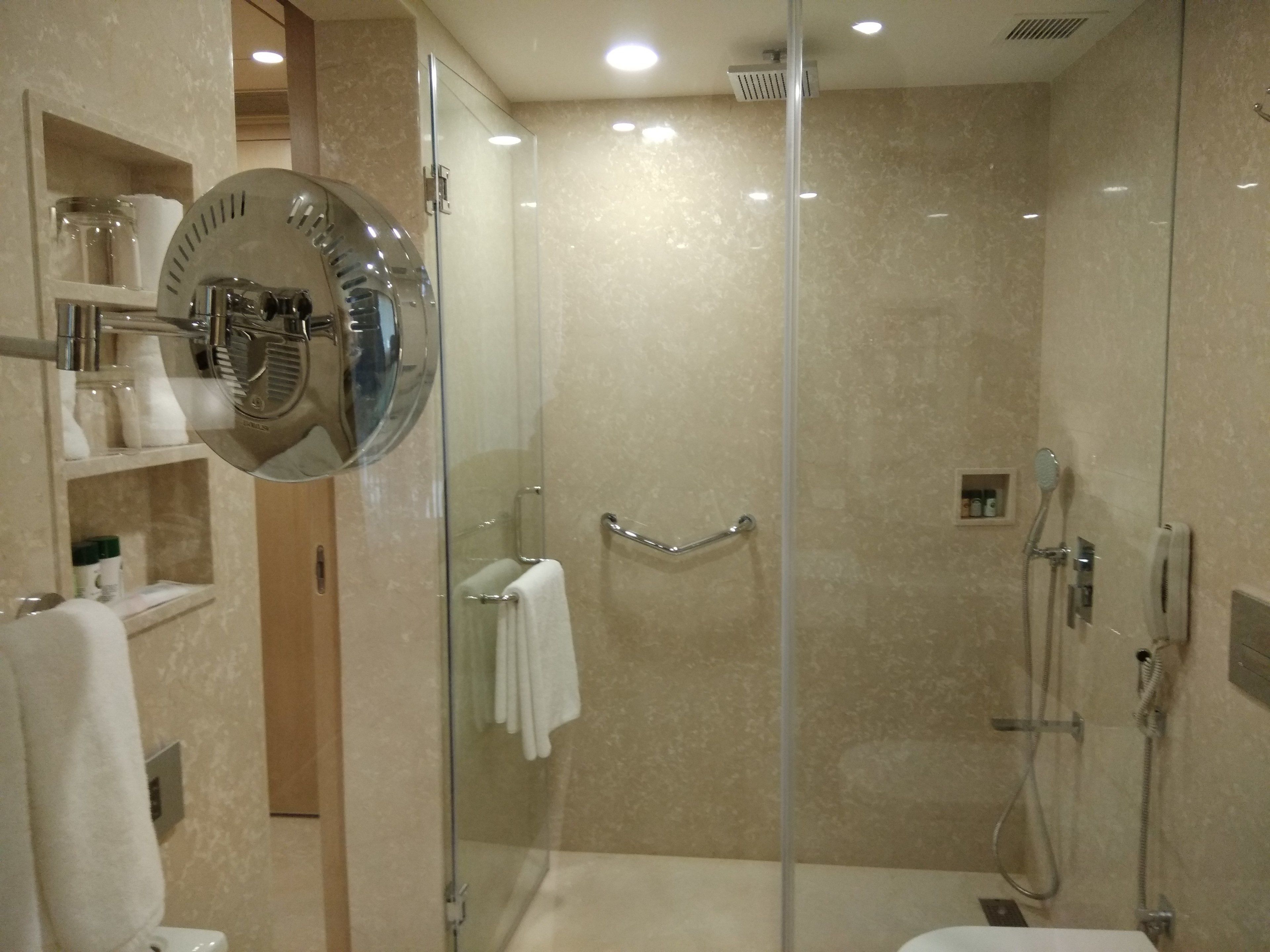 A modern bathroom with a glass-enclosed shower, a built-in toilet, and a vanity with shelves.