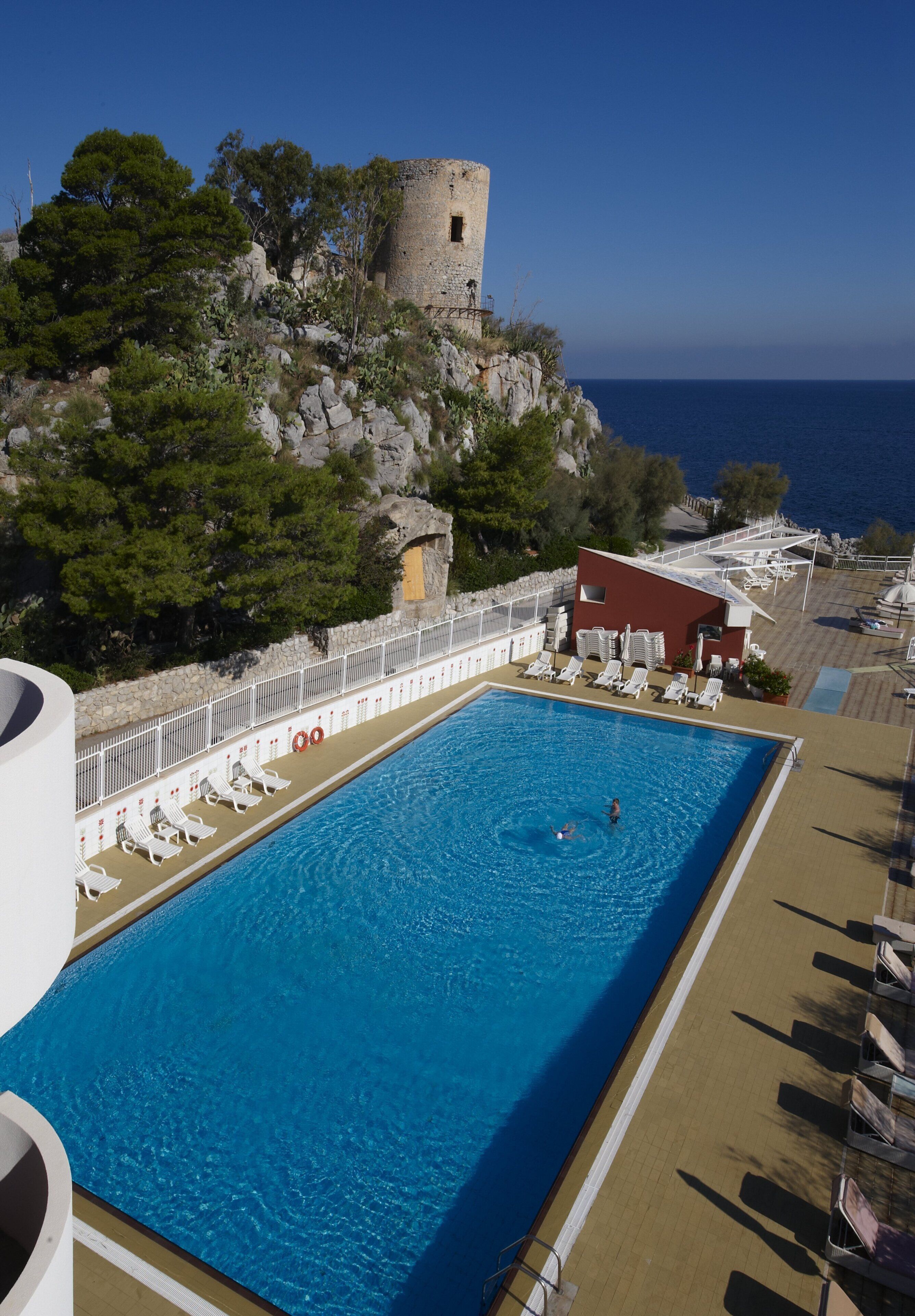 Una piscina con vista al mar y un castillo en un acantilado.