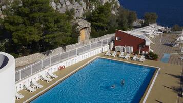 Uma piscina com vista para o mar e um castelo numa falésia.