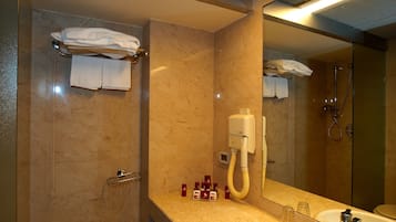 Ein modernes Badezimmer mit großem Spiegel, Waschbecken und Duschbereich.