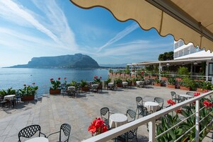 Una terrazza con posti a sedere all'aperto, vista su un lago e una montagna in lontananza.