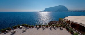A seaside terrace with outdoor seating and a view of the sea and a mountain. - Splendid Hotel La Torre (Palermo)