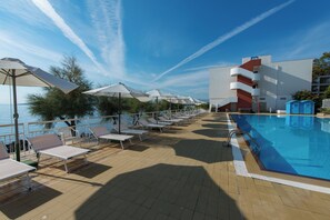 A poolside area with sun loungers and umbrellas, a clear sky, and a view of the sea. - Splendid Hotel La Torre (Palermo)