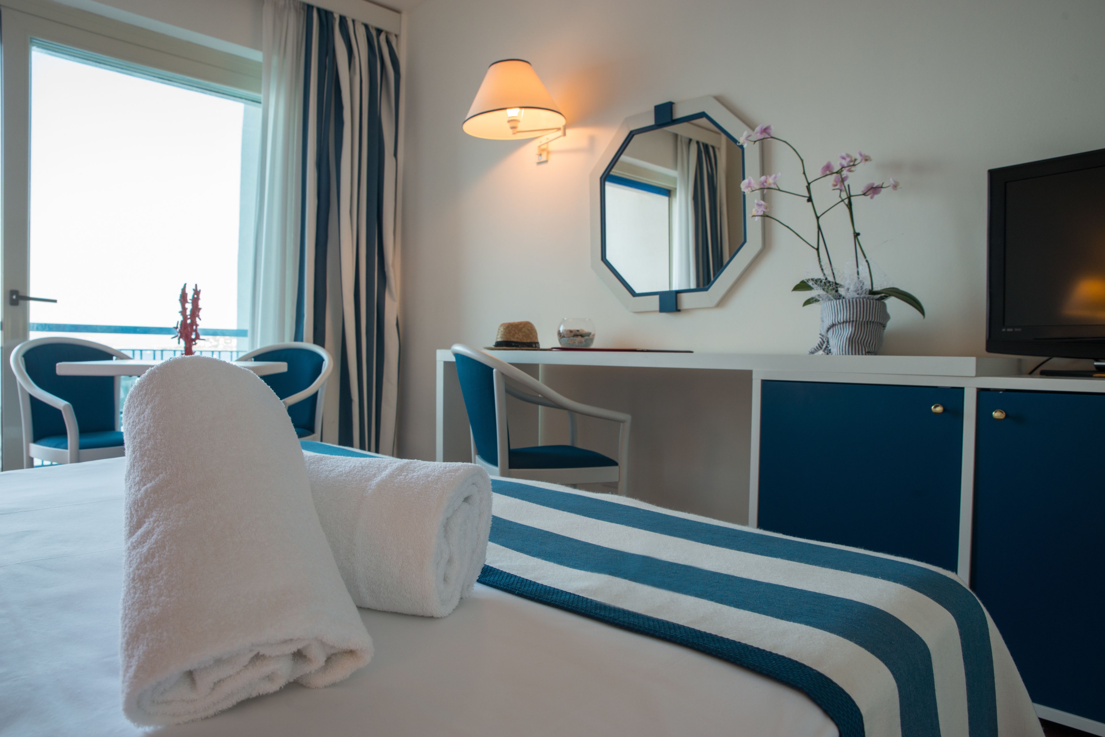 Une chambre d’hôtel équipée d’un lit, d’un bureau, d’une chaise, d’une télévision et d’une fenêtre avec des rideaux.