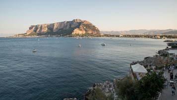 Une vue côtière avec un rivage rocheux, une grande falaise et plusieurs bateaux sur l’eau.