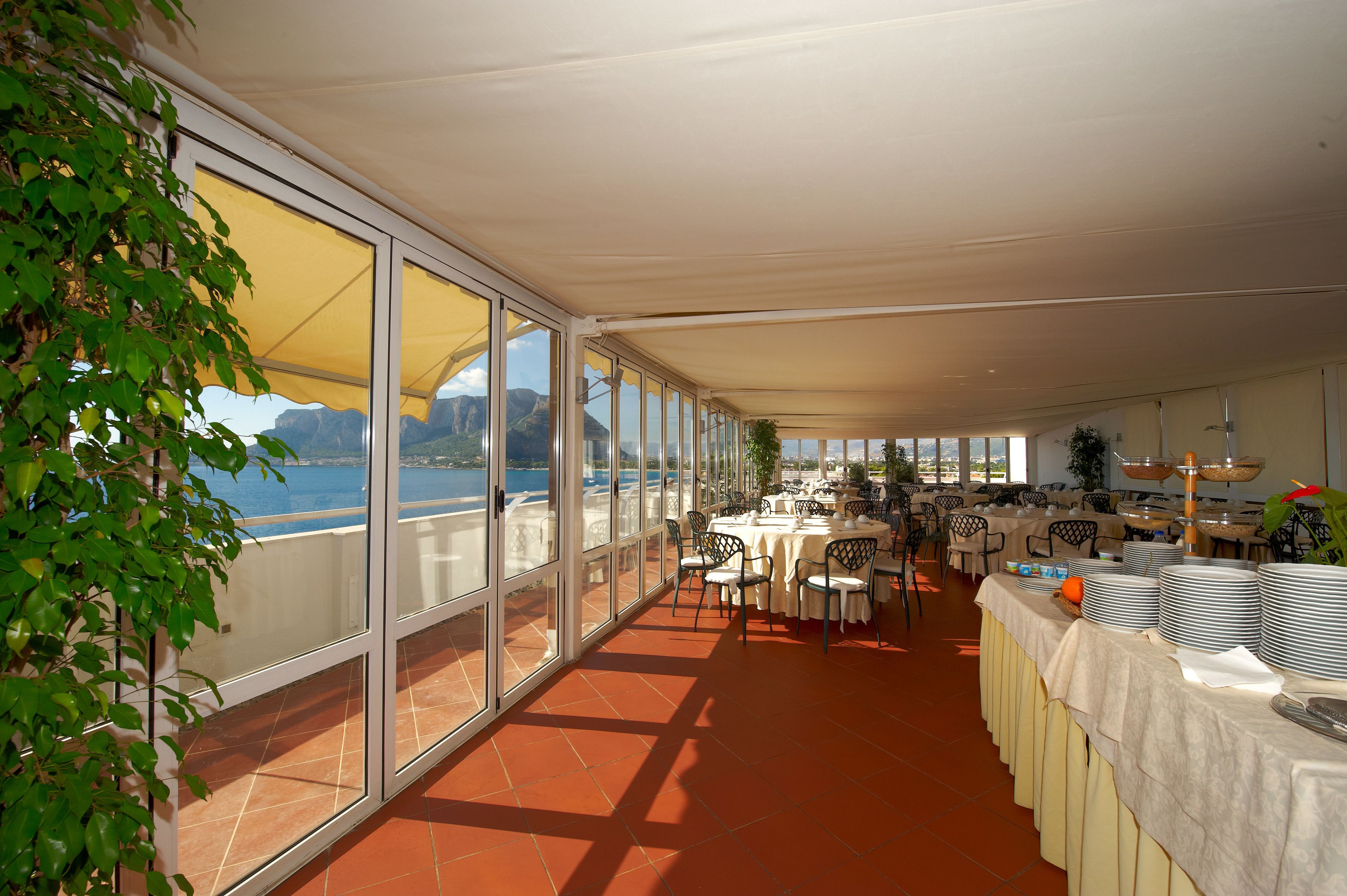 A spacious dining area with large windows offering a view of the sea and mountains.