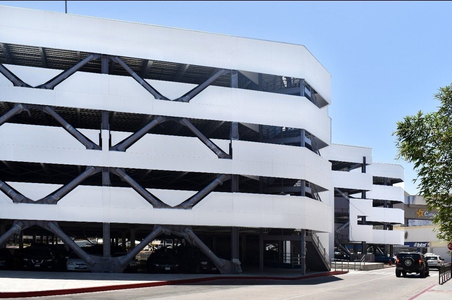 Un estacionamiento de varios pisos con diseño moderno, que presenta un patrón geométrico de paredes blancas y elementos estructurales negros.