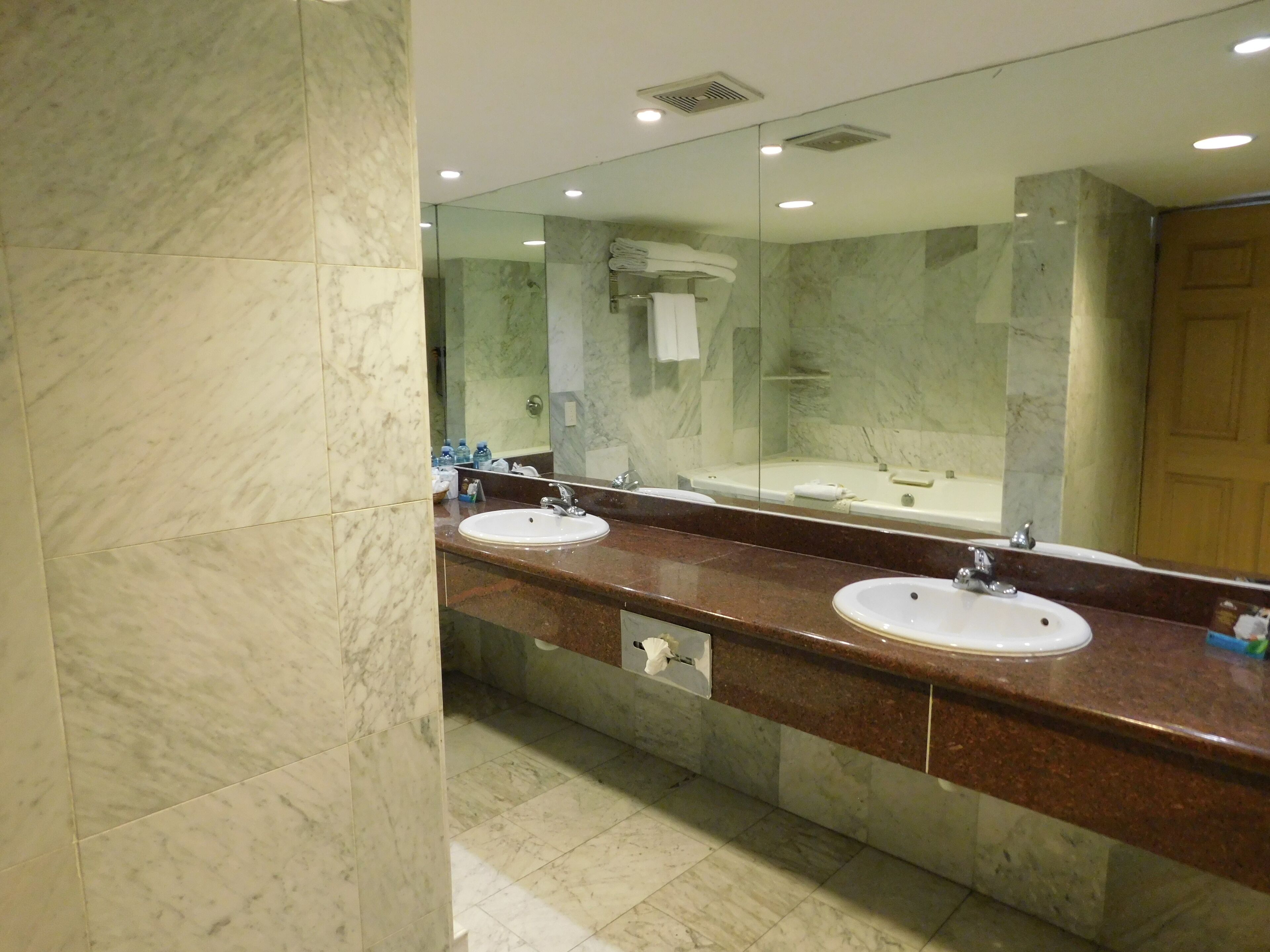 Un baño moderno con dos lavamanos, un espejo grande y una bañera.