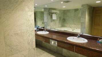Un baño moderno con dos lavamanos, un espejo grande y una bañera.