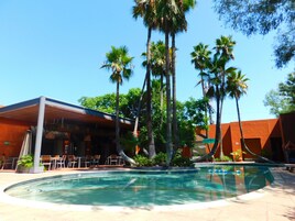 Una piscina al aire libre, sombrillas, sillones reclinables de piscina