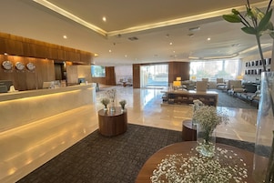 Un moderno vestíbulo de hotel con mostrador de recepción, zona de estar y ventanas amplias.