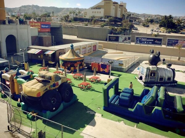 A theme park with a large vehicle ride, a carousel, and various food and drink advertisements.