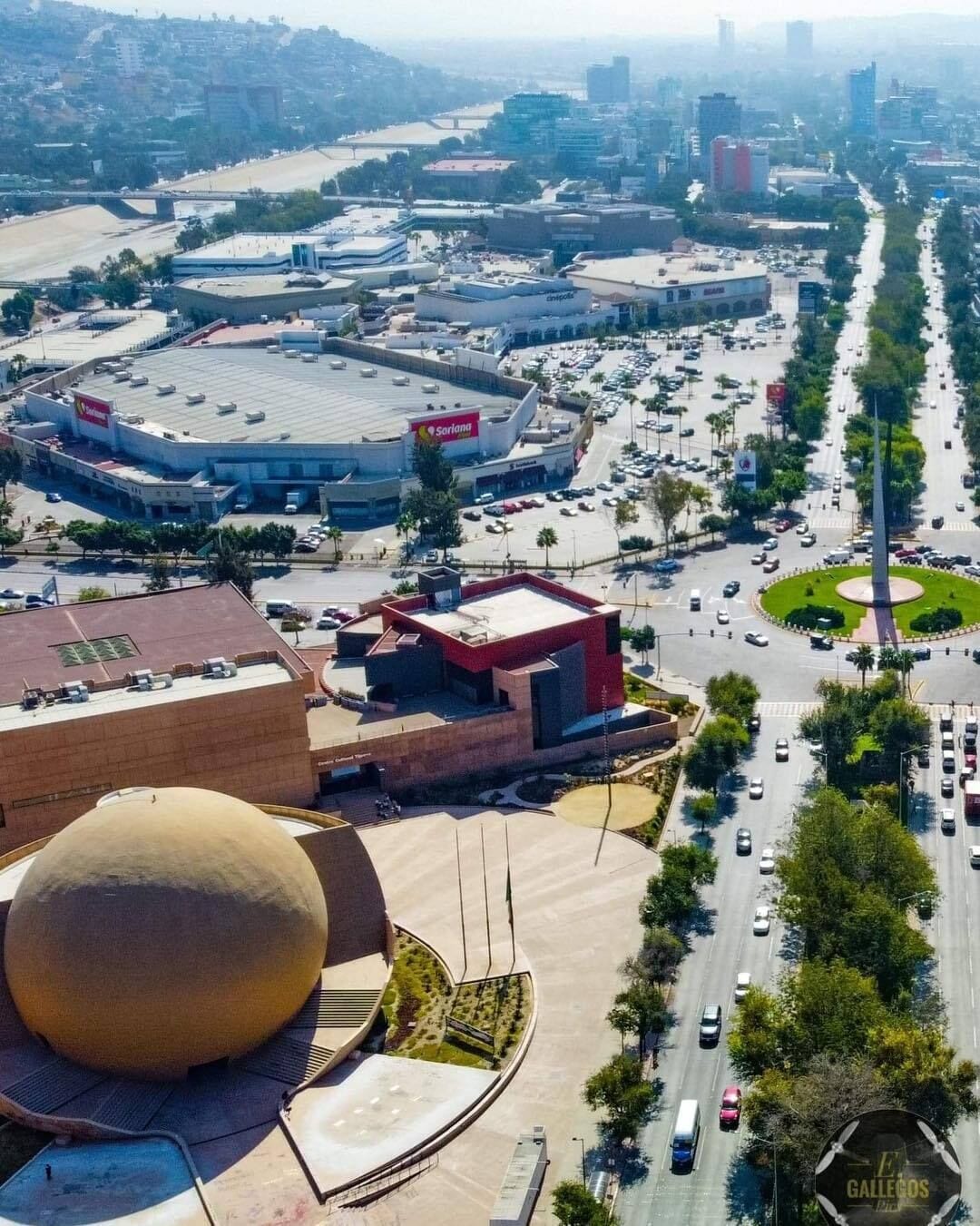 A large commercial area with a prominent circular building and a modern structure with a red roof.