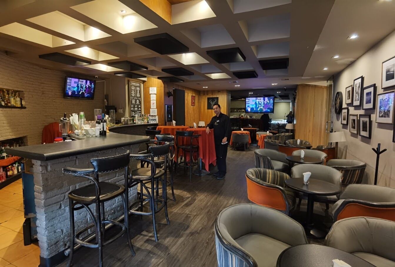 A bar area with stools, tables, and a counter.